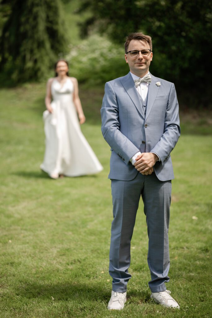 First Look Hochzeit im Hofgut Hohenstein, Bräutigam wartet im Grünen auf die Braut