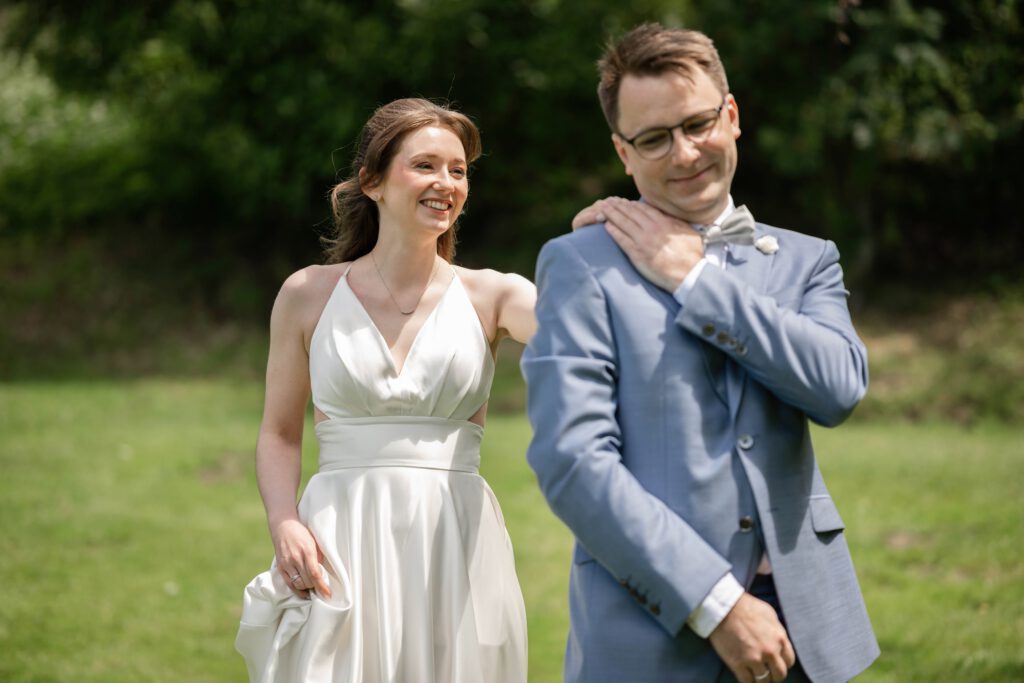 First Look Hochzeit im Hofgut Hohenstein, Braut berührt Bräutigam von hinten