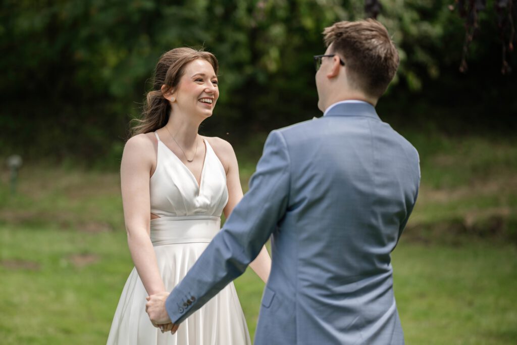 Braut und Bräutigam lachen und halten sich an den Händen im Hofgut Hohenstein