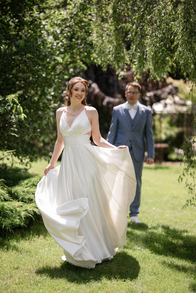 Braut geht durch den Garten, Bräutigam folgt beim Paarshooting im Hofgut Hohenstein