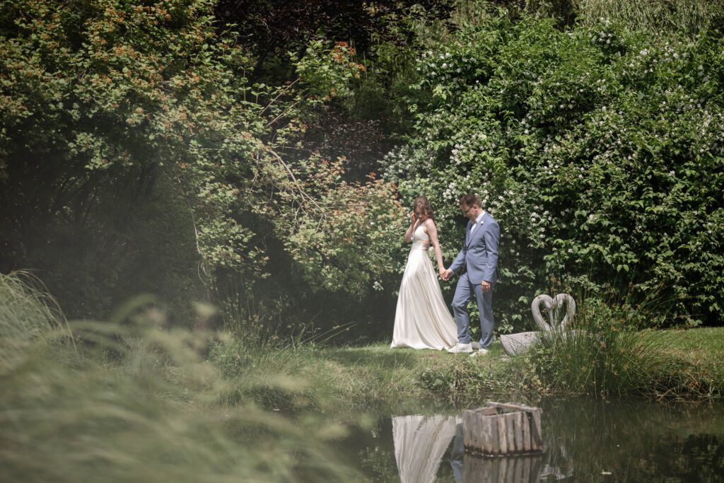 Brautpaar geht Hand in Hand am Teich im Hofgut Hohenstein