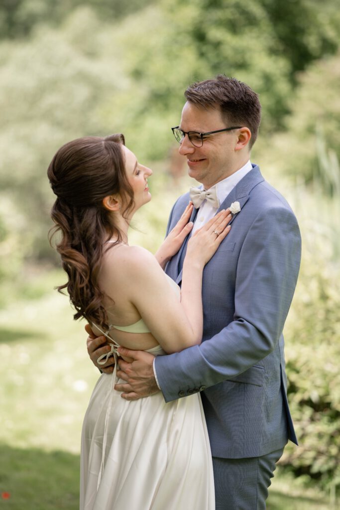 Braut legt die Hände auf das Revers des Bräutigams im Hofgut Hohenstein