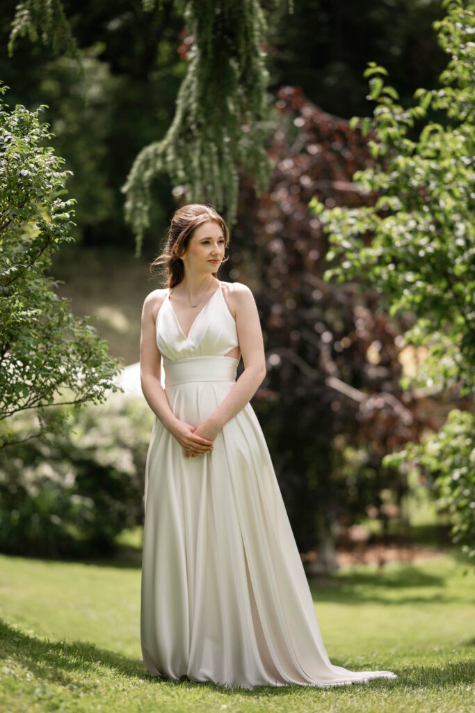 Braut steht allein im Grünen beim Hochzeitsshooting im Hofgut Hohenstein