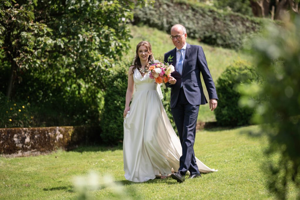 Braut und Vater gehen durch die Gäste bei der freien Trauung im Hofgut Hohenstein