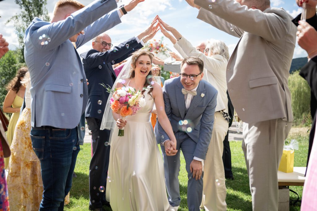 Brautpaar lacht beim Auszug mit Seifenblasen im Hofgut Hohenstein