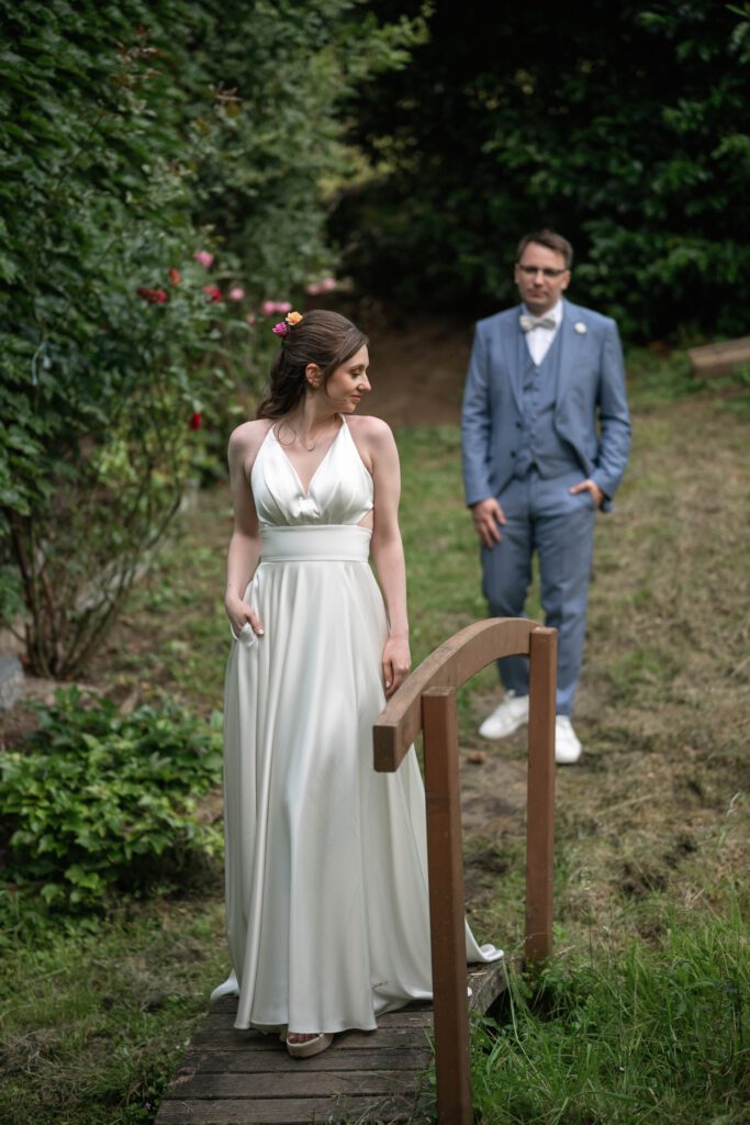 Braut geht über eine Holzbrücke, Bräutigam folgt im Hofgut Hohenstein