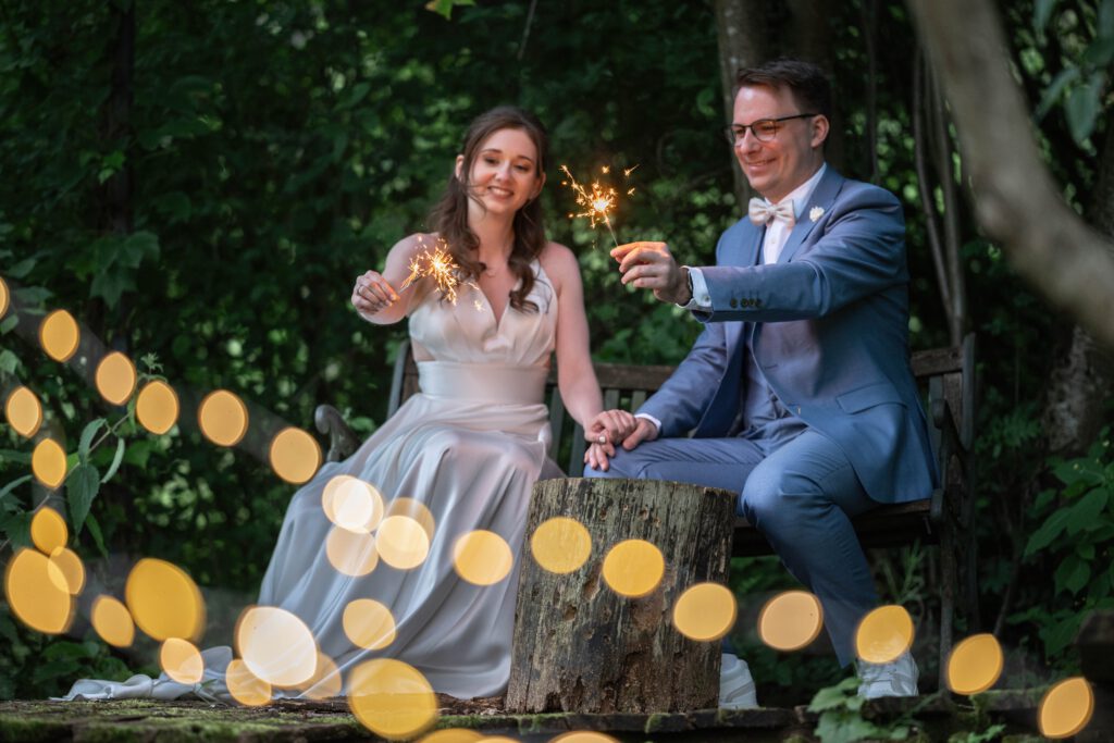 Brautpaar sitzt mit Wunderkerzen am Abend im Hofgut Hohenstein