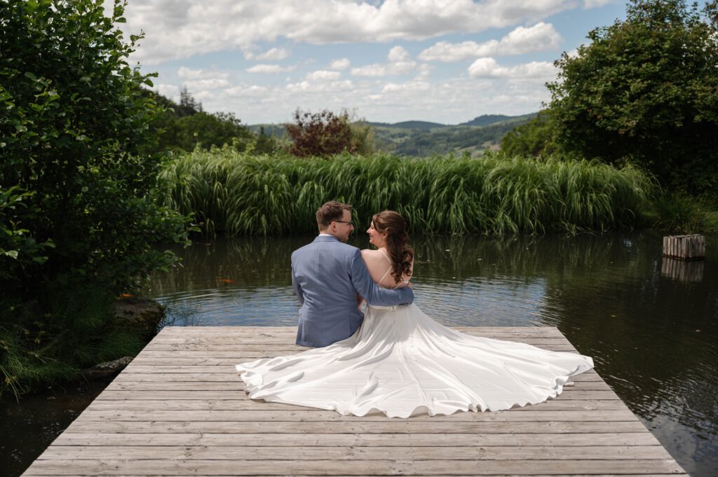 Brautpaar sitzt am Steg am Wasser im Hofgut Hohenstein