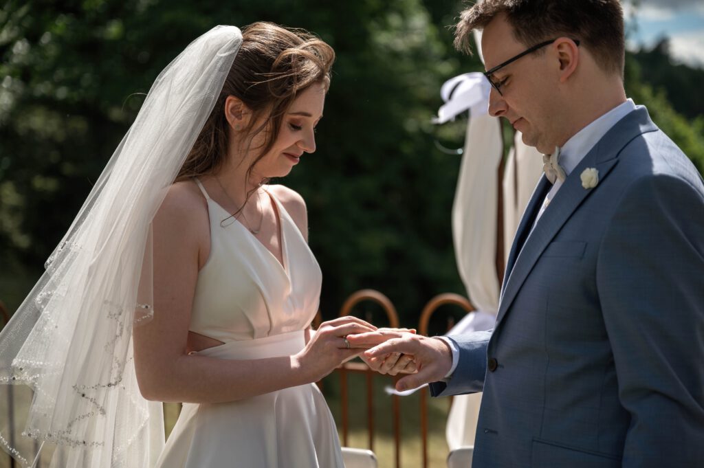 Braut steckt dem Bräutigam den Ring bei der Hochzeit im Hofgut Hohenstein an