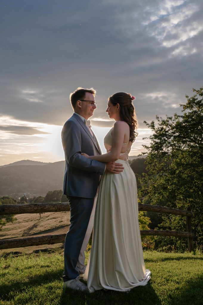 Braut und Bräutigam stehen sich im Gegenlicht bei Sonnenuntergang im Hofgut Hohenstein gegenüber