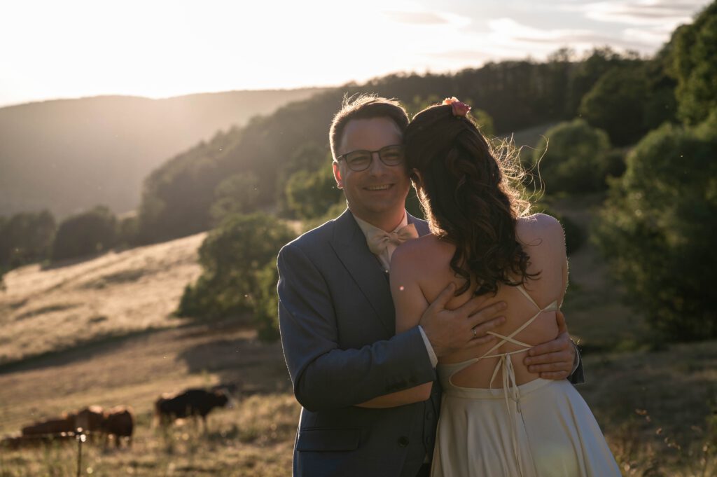 Bräutigam umarmt die Braut bei Sonnenuntergang im Hofgut Hohenstein