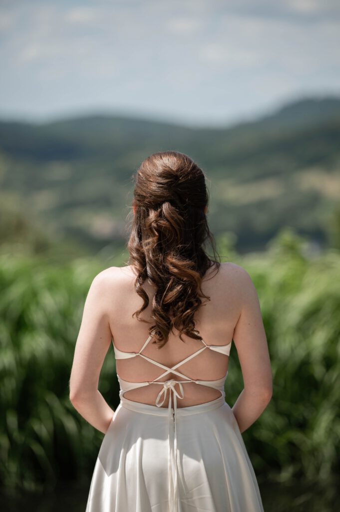Braut von hinten mit offenem Rückenblick auf die Landschaft im Hofgut Hohenstein