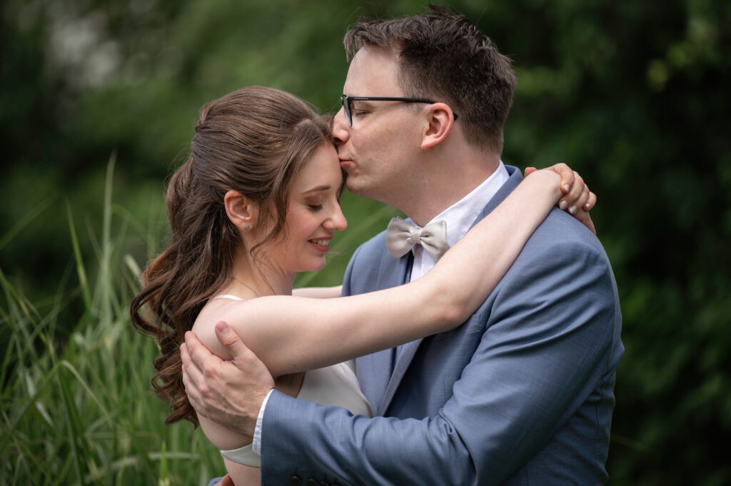 Bräutigam küsst die Braut auf die Stirn im Hofgut Hohenstein