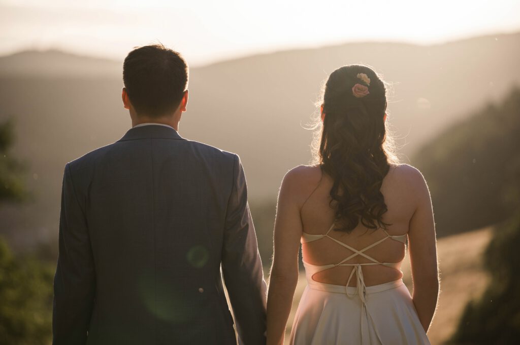 Braut und Bräutigam von hinten mit Blick auf die Landschaft bei Sonnenuntergang im Hofgut Hohenstein